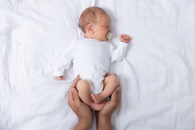 Photo of Father with his cute newborn baby on bed, top view