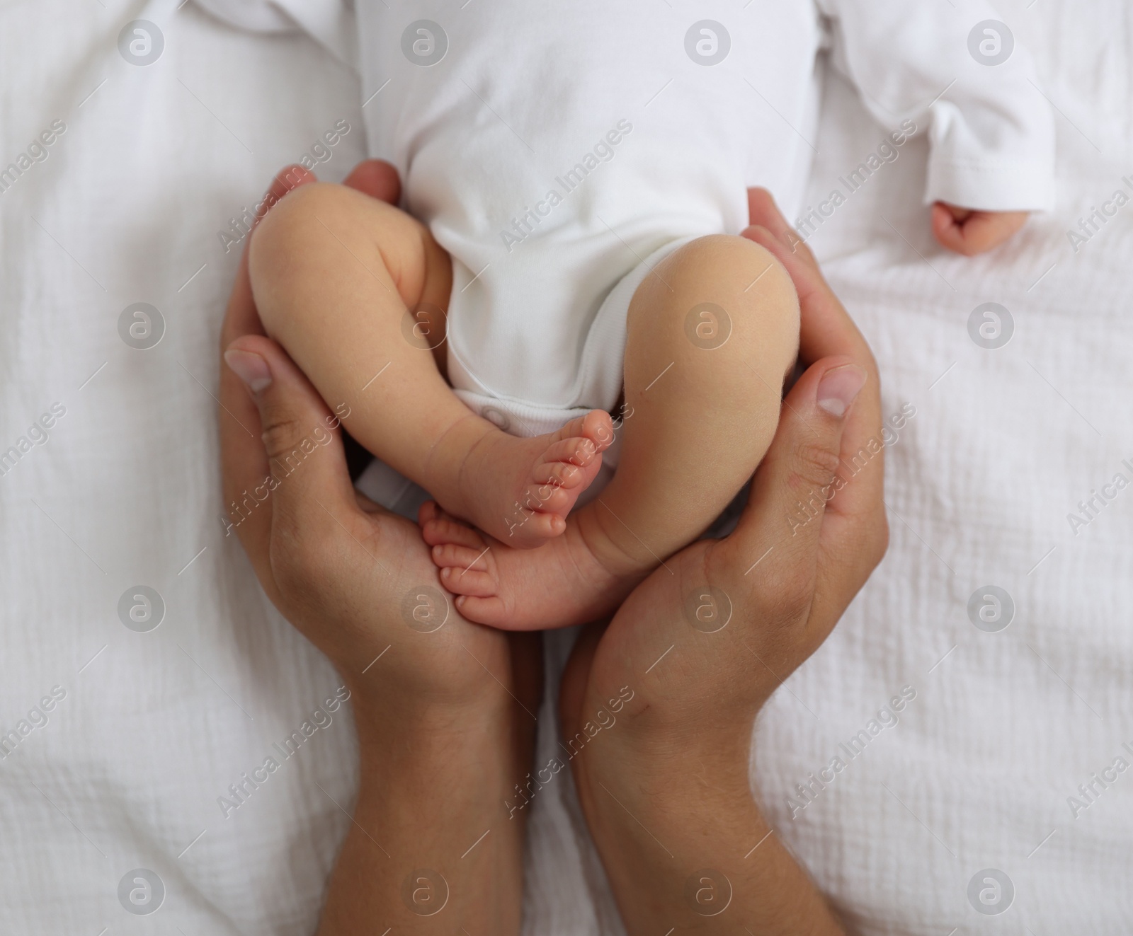 Photo of Father with his cute newborn baby on bed, top view