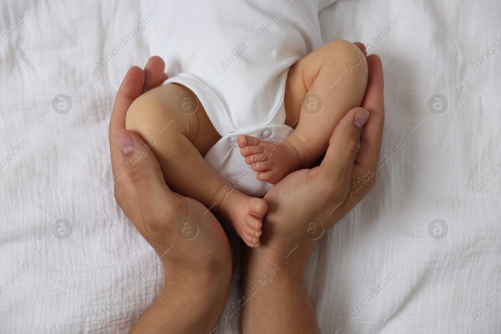 Photo of Father with his cute newborn baby on bed, top view