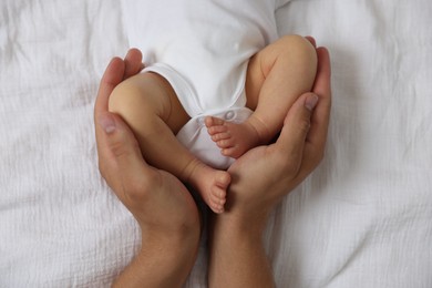 Photo of Father with his cute newborn baby on bed, top view