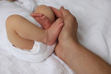 Photo of Father with his cute newborn baby on bed, closeup