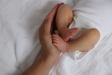 Photo of Father with his cute newborn baby on bed, top view