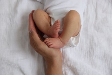 Photo of Father with his cute newborn baby on bed, top view