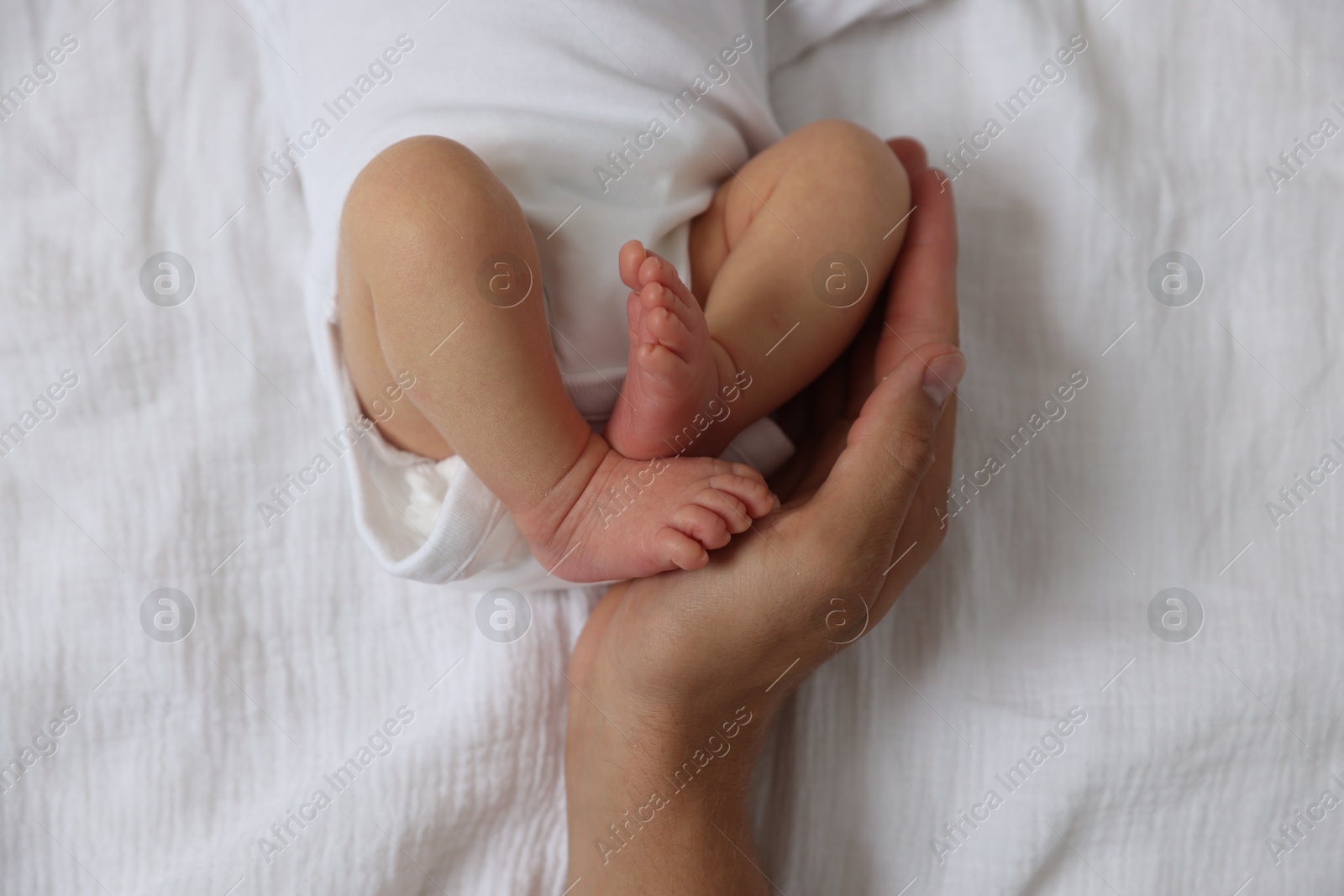 Photo of Father with his cute newborn baby on bed, top view