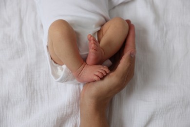 Photo of Father with his cute newborn baby on bed, top view