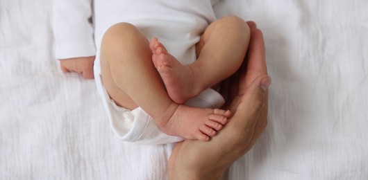 Photo of Father with his cute newborn baby on bed, top view