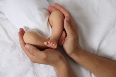 Photo of Father with his cute newborn baby on bed, top view