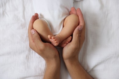 Photo of Father with his cute newborn baby on bed, top view
