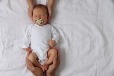 Photo of Parents with their cute newborn baby on bed, top view. Space for text