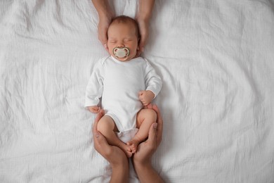 Photo of Parents with their cute newborn baby on bed, top view