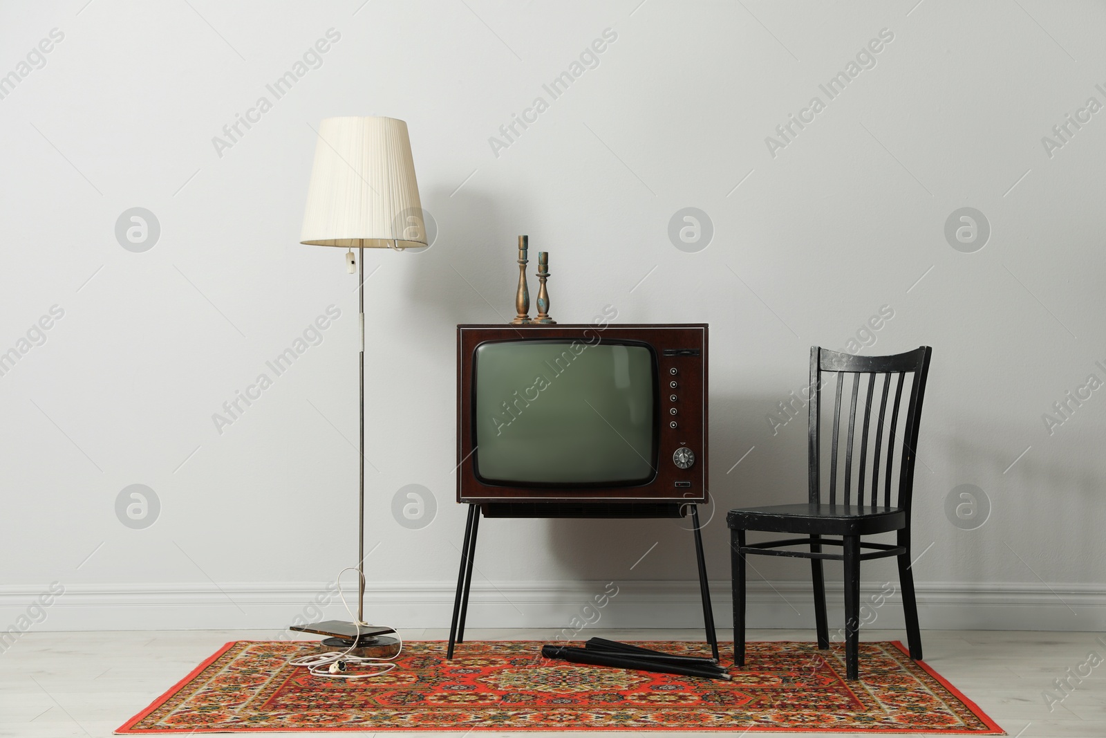 Retro TV on stand, black chair and lamp near white wall. Used stuff Photo of Retro TV on stand, black chair and lamp near white wall. Used stuff