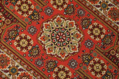 Photo of Soft red carpet with pattern as background, top view. Used stuff