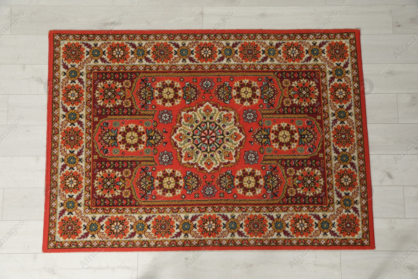 Soft red carpet with pattern on light wooden floor, top view. Used stuff Photo of Soft red carpet with pattern on light wooden floor, top view. Used stuff