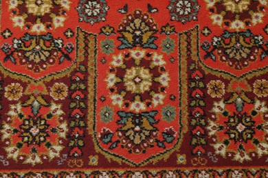 Photo of Soft red carpet with pattern as background, top view. Used stuff