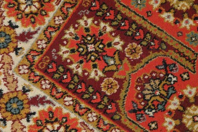 Photo of Soft red carpet with pattern as background, top view. Used stuff