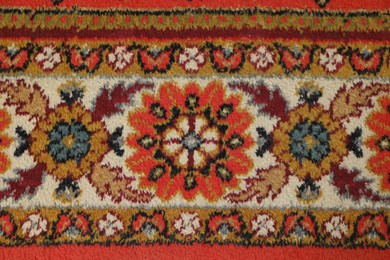 Photo of Soft red carpet with pattern as background, top view. Used stuff