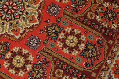Photo of Soft red carpet with pattern as background, top view. Used stuff