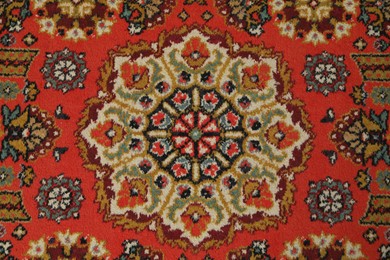Photo of Soft red carpet with pattern as background, top view. Used stuff