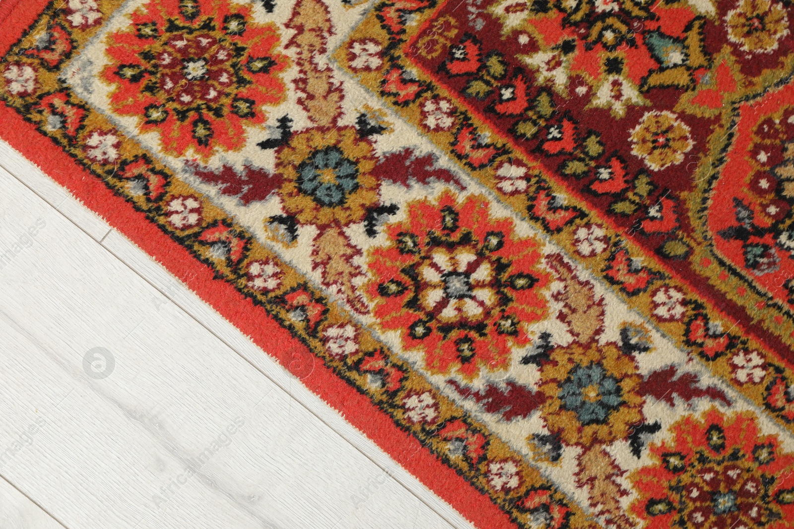 Soft red carpet with pattern on light wooden floor, top view. Used stuff Photo of Soft red carpet with pattern on light wooden floor, top view. Used stuff