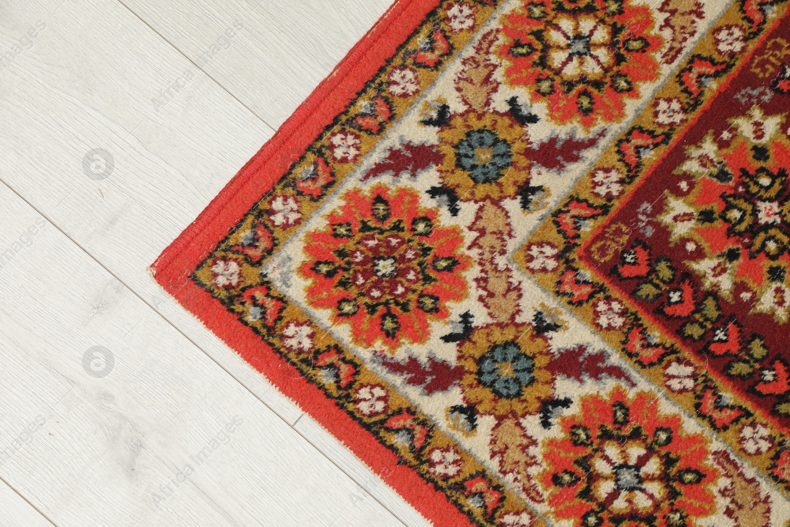 Soft red carpet with pattern on light wooden floor, top view. Used stuff Photo of Soft red carpet with pattern on light wooden floor, top view. Used stuff
