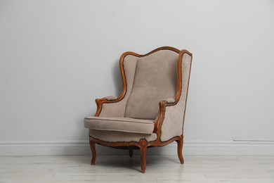 Photo of Old-fashioned armchair near light grey wall. Used stuff