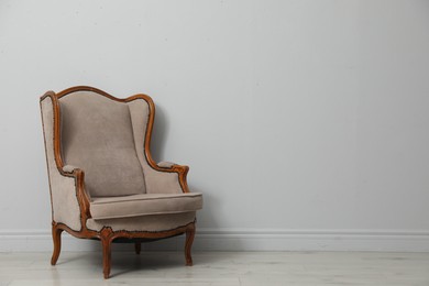 Photo of Old-fashioned armchair near light grey wall, space for text. Used stuff