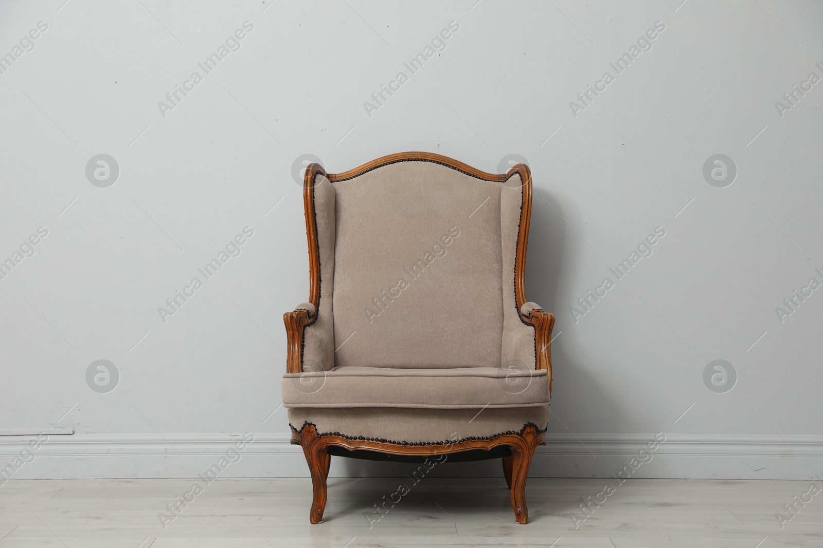 Old-fashioned armchair near light grey wall. Used stuff Photo of Old-fashioned armchair near light grey wall. Used stuff