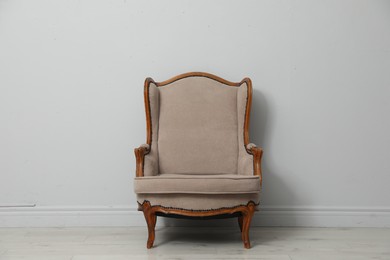 Photo of Old-fashioned armchair near light grey wall. Used stuff