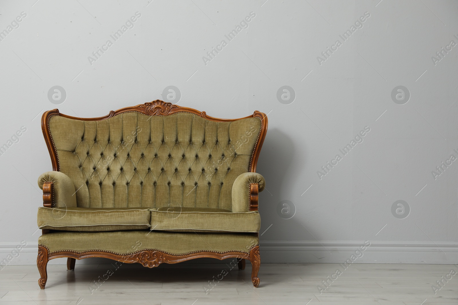 Old-fashioned sofa near light grey wall, space for text. Used stuff Photo of Old-fashioned sofa near light grey wall, space for text. Used stuff