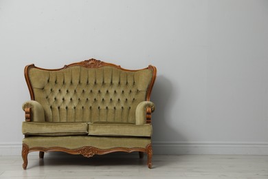 Photo of Old-fashioned sofa near light grey wall, space for text. Used stuff