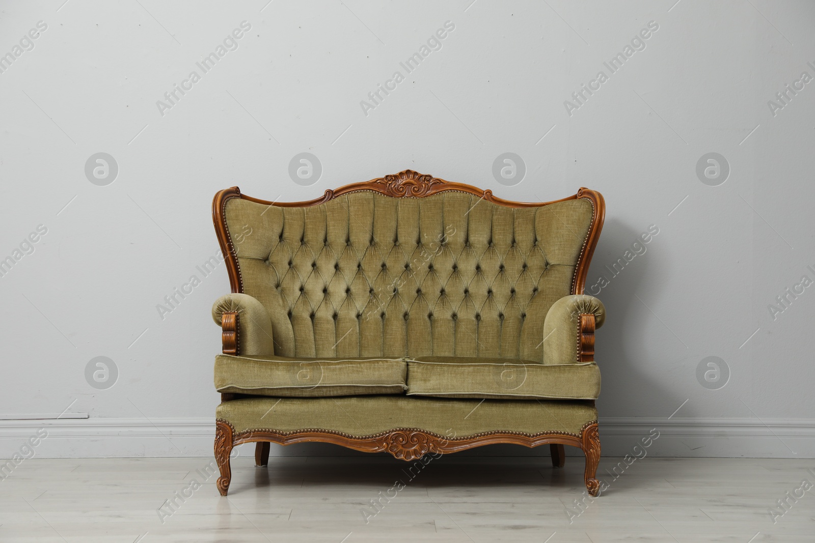 Old-fashioned sofa near light grey wall. Used stuff Photo of Old-fashioned sofa near light grey wall. Used stuff