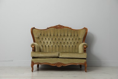 Photo of Old-fashioned sofa near light grey wall. Used stuff