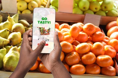 Image of Food delivery. Man using mobile phone app to order grocery online, closeup