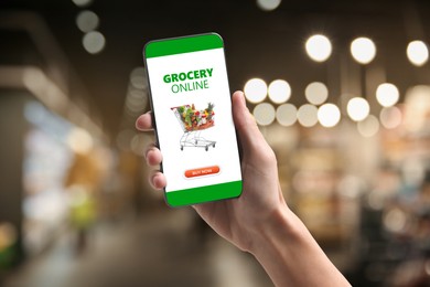 Image of Food delivery. Man using mobile phone app to order grocery online, closeup