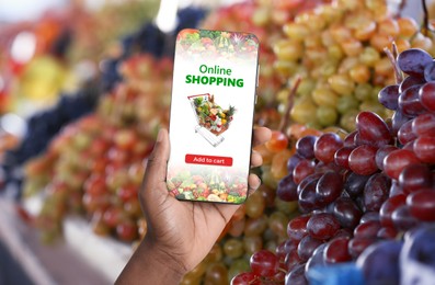 Image of Food delivery. Man using mobile phone app to order grocery online, closeup