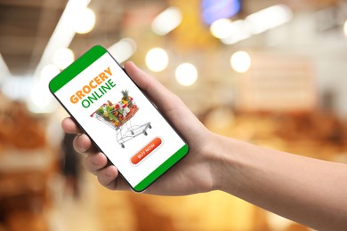 Image of Food delivery. Man using mobile phone app to order grocery online, closeup