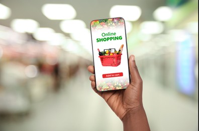 Image of Food delivery. Man using mobile phone app to order grocery online, closeup