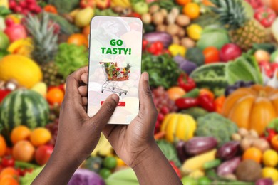 Image of Food delivery. Man using mobile phone app to order grocery online, closeup