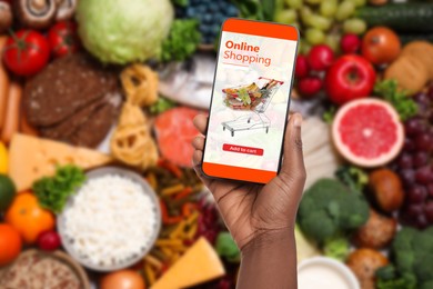 Image of Food delivery. Man using mobile phone app to order grocery online, closeup