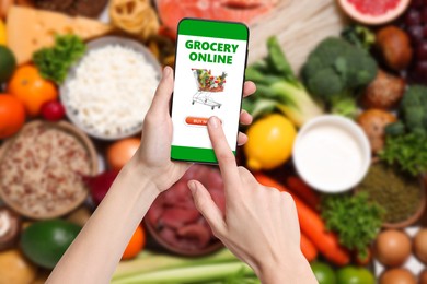 Image of Food delivery. Man using mobile phone app to order grocery online, closeup