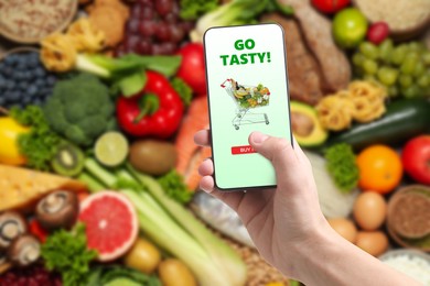 Image of Food delivery. Man using mobile phone app to order grocery online, closeup
