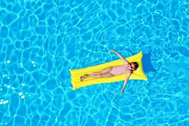 Photo of Girl on inflatable mattress in swimming pool, top view. Summer vacation