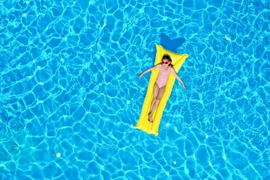 Photo of Girl on inflatable mattress in swimming pool, top view. Summer vacation