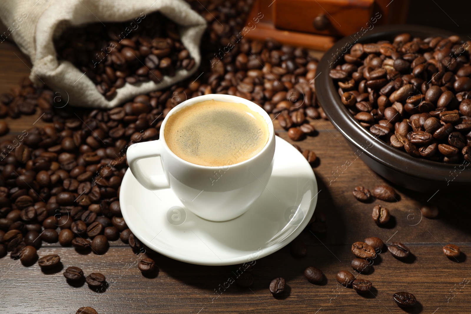 Aromatic coffee in cup and beans on wooden table, closeup Photo of Aromatic coffee in cup and beans on wooden table, closeup