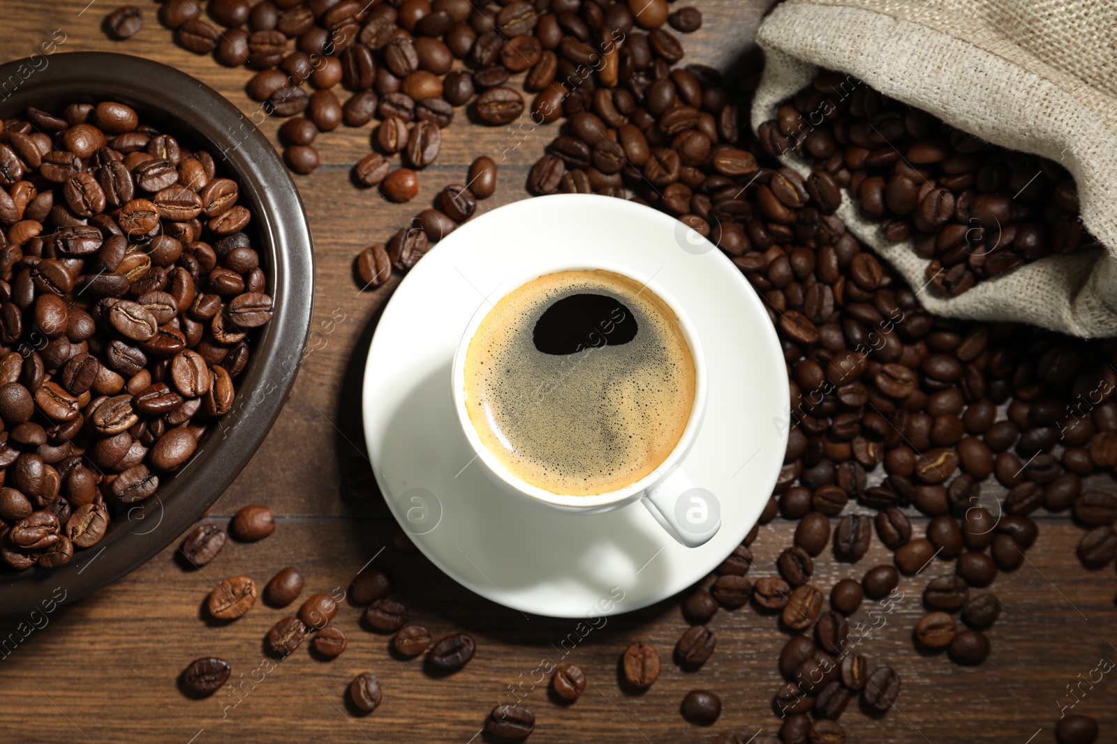 Aromatic coffee in cup and beans on wooden table, flat lay Photo of Aromatic coffee in cup and beans on wooden table, flat lay