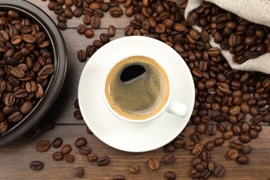 Photo of Aromatic coffee in cup and beans on wooden table, flat lay