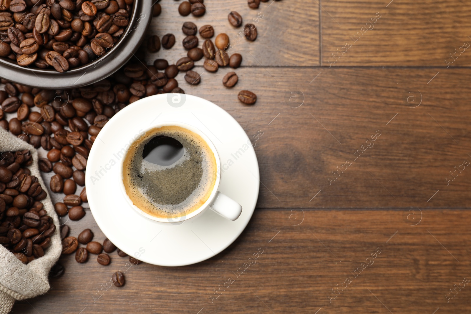 Aromatic coffee in cup and beans on wooden table, flat lay. Space for text Photo of Aromatic coffee in cup and beans on wooden table, flat lay. Space for text
