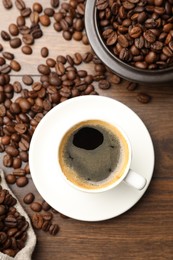 Photo of Aromatic coffee in cup and beans on wooden table, flat lay