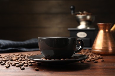 Photo of Aromatic coffee in cup, beans, cezve and grinder on wooden table, closeup