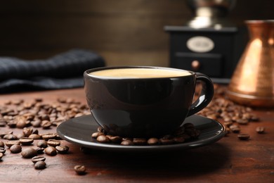 Photo of Aromatic coffee in cup, beans, cezve and grinder on wooden table, closeup